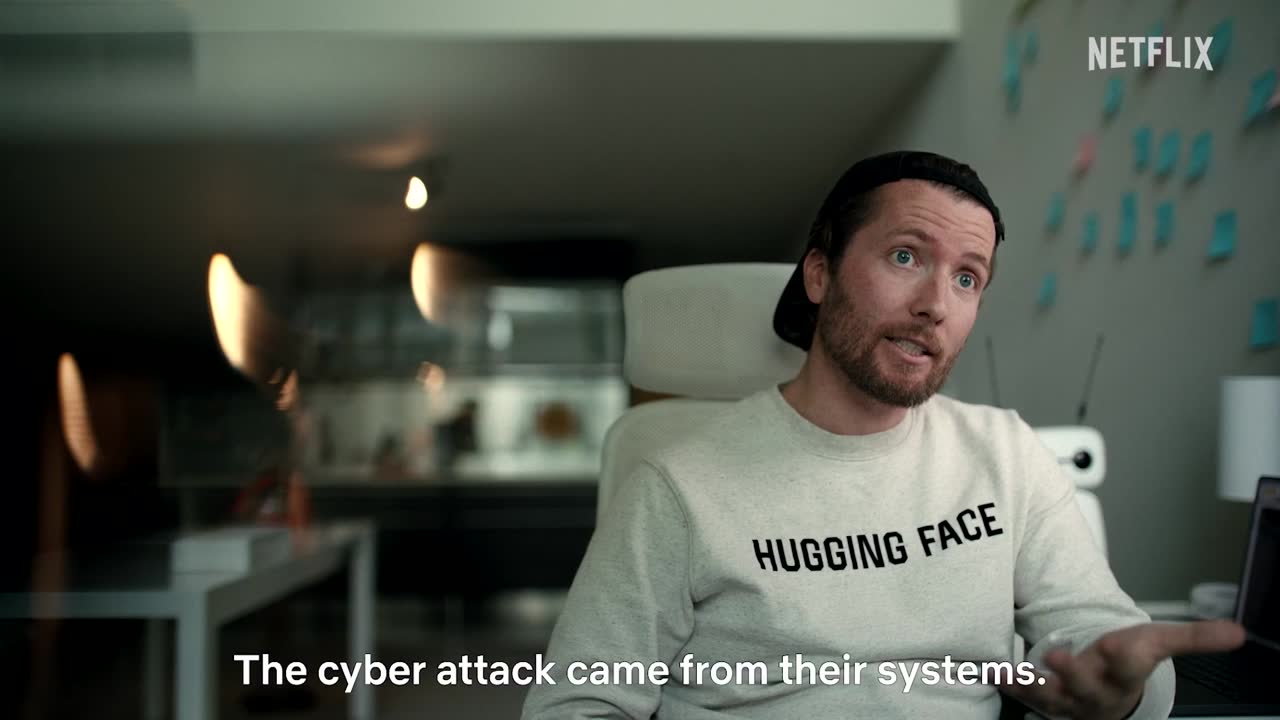 Man in een Hugging Face-trui in de Netflix-teaser, ondertitel: The cyber attack came from their systems